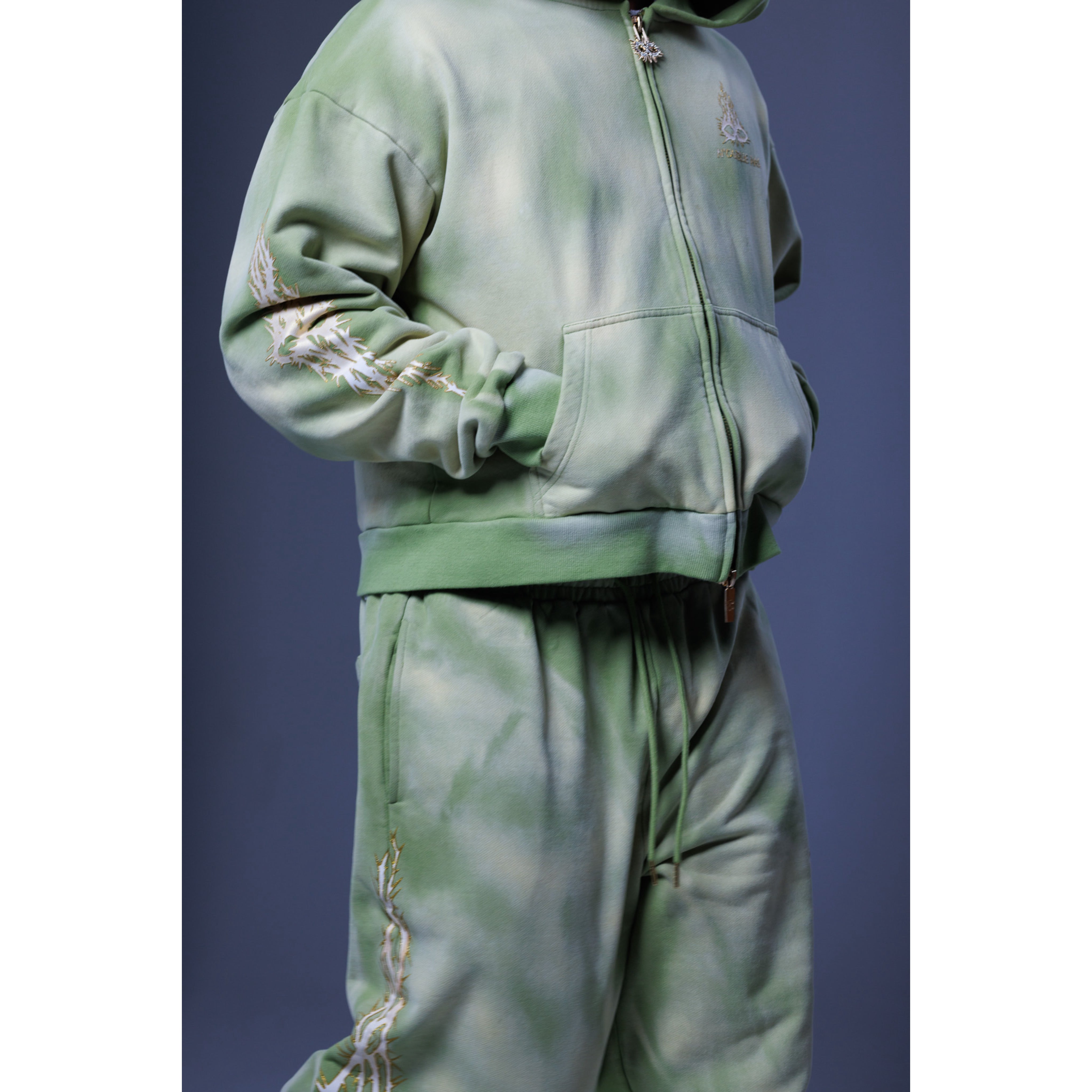 Green tracksuit with chain details on a blue background