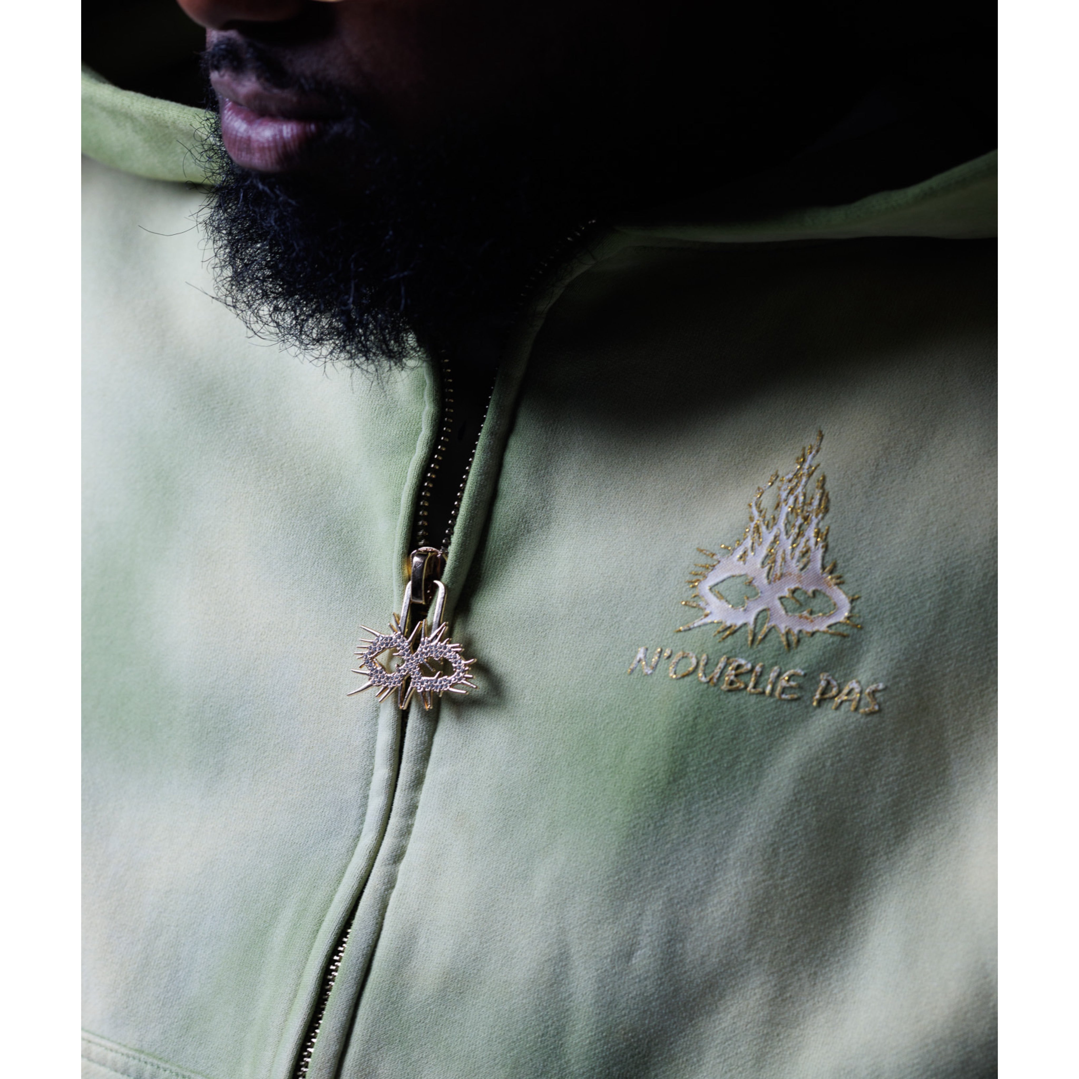 Close-up of a green jacket with a zipper and screenprint design on a dark background