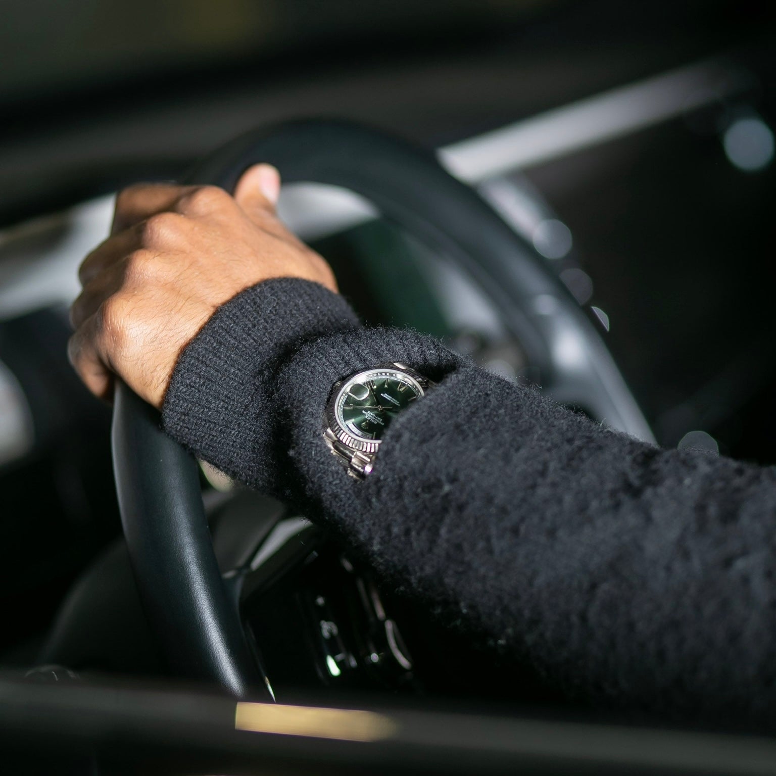 Hand on steering wheel with a watch, inside a car